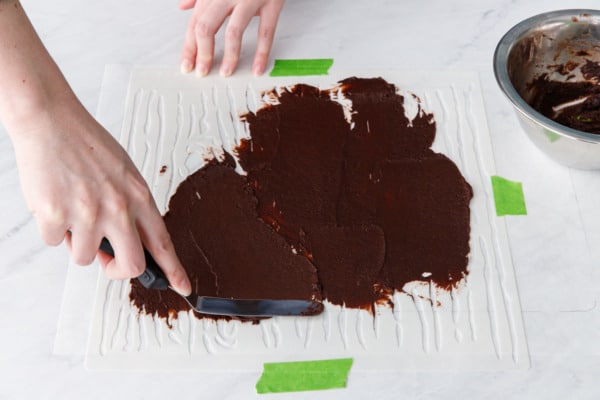 Spreading the chocolate design paste over the wood grain stencil