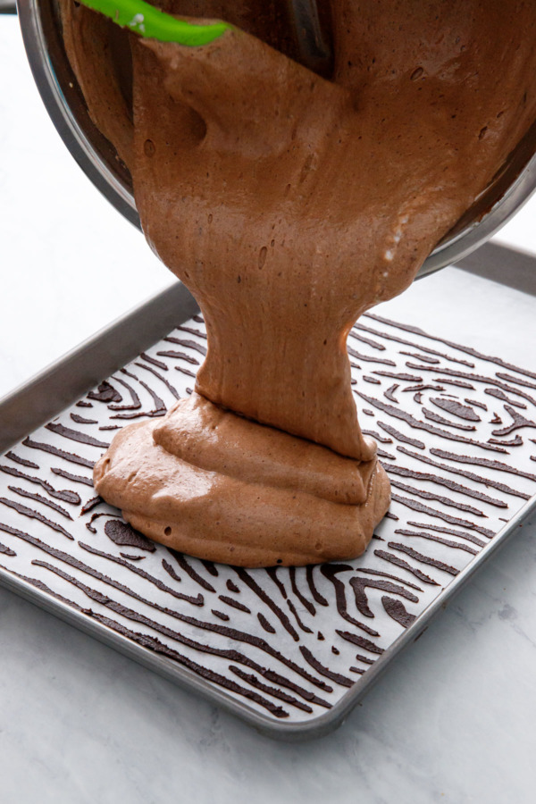 Pouring the chocolate sponge batter onto the parchment-lined jelly roll pan