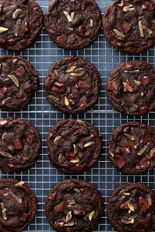 Overhead, even rows of dark chocolate ginger cookies on a silver grid cooling rack