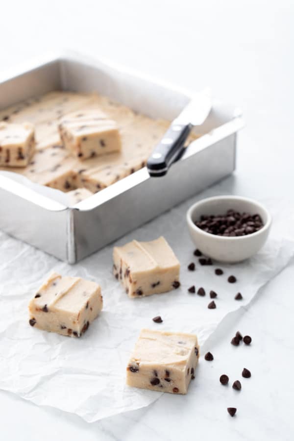 Pan of Chocolate Chip Cookie Dough Fudge, a few pieces cut out and a bowl of mini chocolate chips