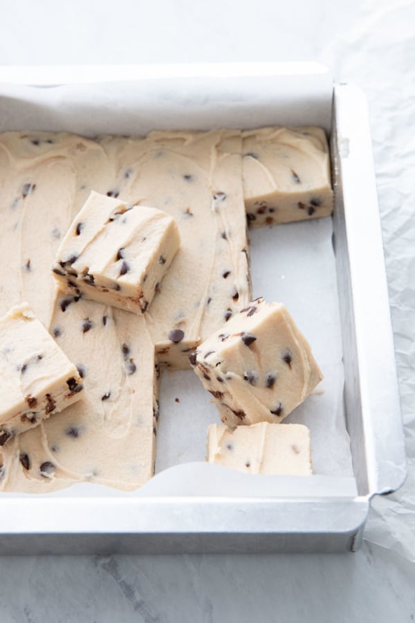 Pan of Chocolate Chip Cookie Dough Fudge with a few pieces cut and sitting on top
