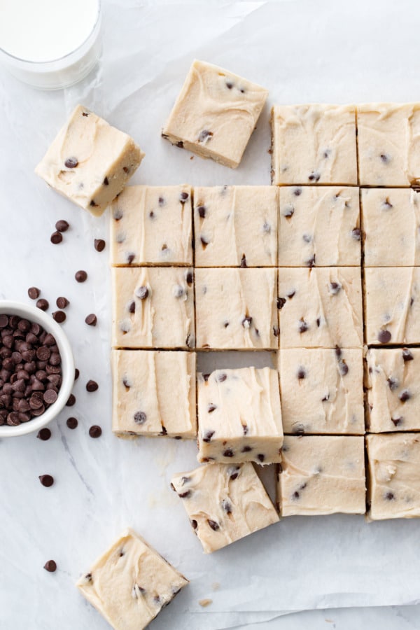 Overhead, squares of Chocolate Chip Cookie Dough Fudge on parchment with chocolate chips