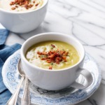 Two big white mugs with Split Pea Soup, with blue napkin and spoons