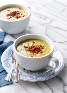 Two big white mugs with Split Pea Soup, with blue napkin and spoons