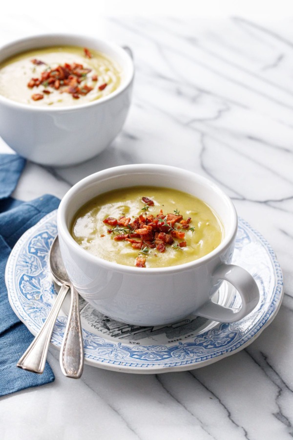 Two big white mugs with Split Pea Soup, with blue napkin and spoons