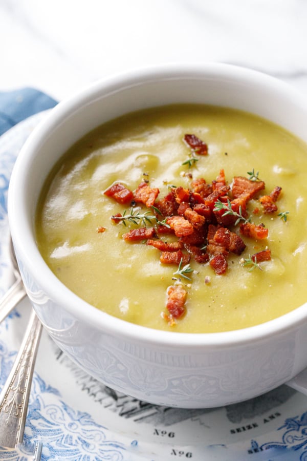 Closeup of cup of Split Pea Soup topped with crispy bacon bits and thyme