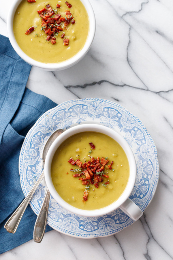 Overhead, two white mugs of Split Pea Soup on a vintage blue plate, blue linen, marble background