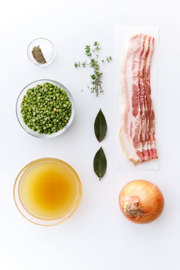 Overhead ingredients to make Split Pea Soup: Bacon, Onion, Split Peas, Bay Leaf, Thyme, Chicken Stock, Salt & Pepper