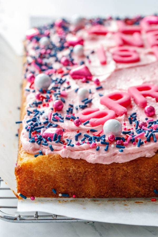 Closeup side view of yellow cake with pink frosting and Valentine's sprinkles