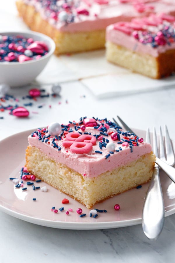 Slice of Classic Yellow Sheet Cake with Strawberry Rose Buttercream on pink plate with fork, showing tender texture of yellow cake