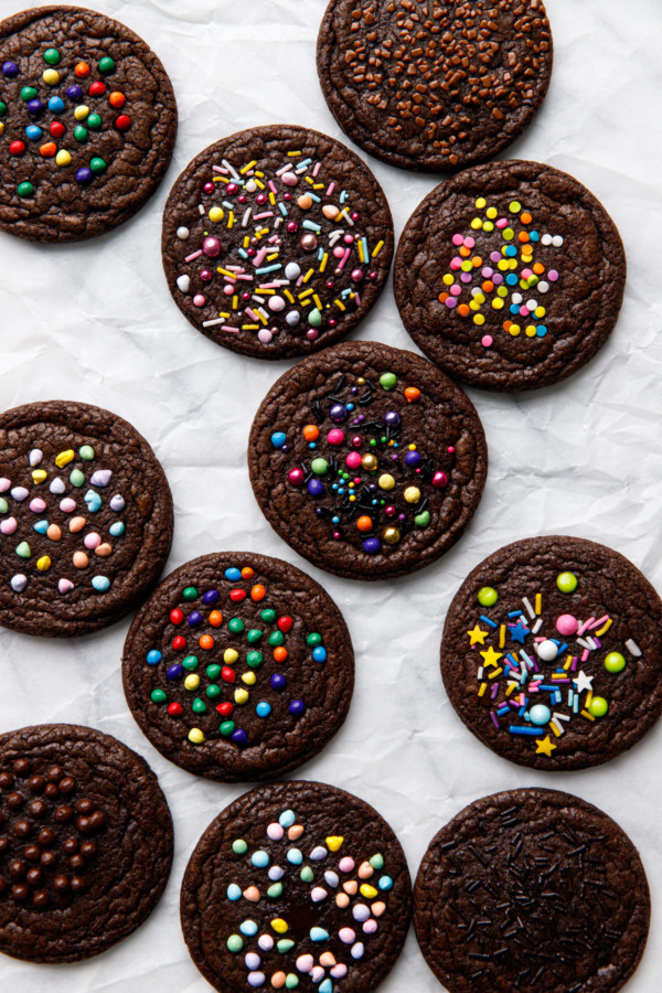 Overhead, brownie cookies on parchment paper with different varieties of sprinkles