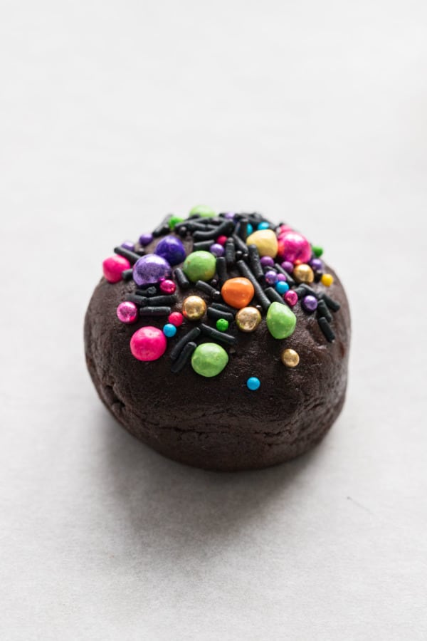 Closeup ball of brownie cookie dough topped with colorful rainbow sprinkles