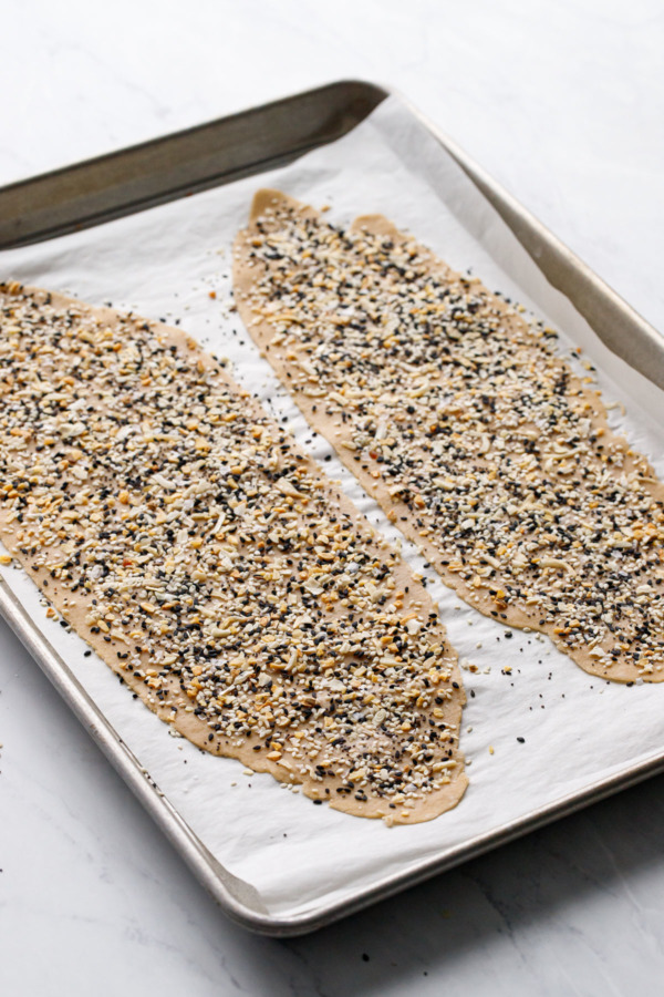 Two crackers on a parchment-lined baking sheet prior to baking