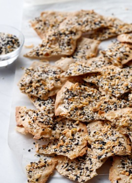 Broken pieces of Homemade Everything Crackers with small bowl of everything spice.