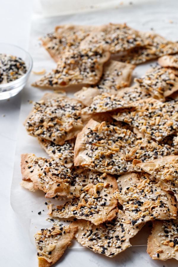 Broken pieces of Homemade Everything Crackers with small bowl of everything spice.