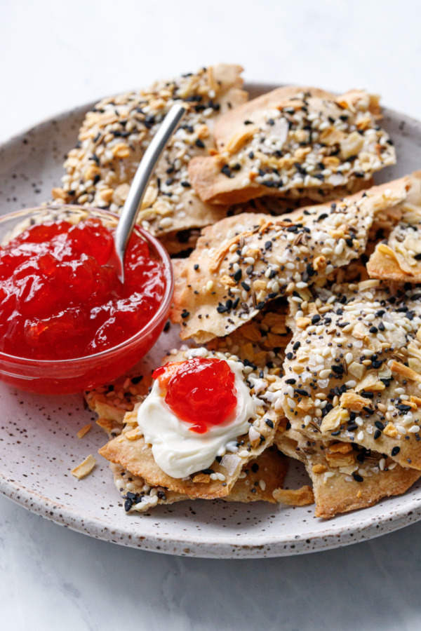 Plate with Homemade Everything Crackers, bowl of pepper jelly, one cracker topped with cream cheese and pepper jelly