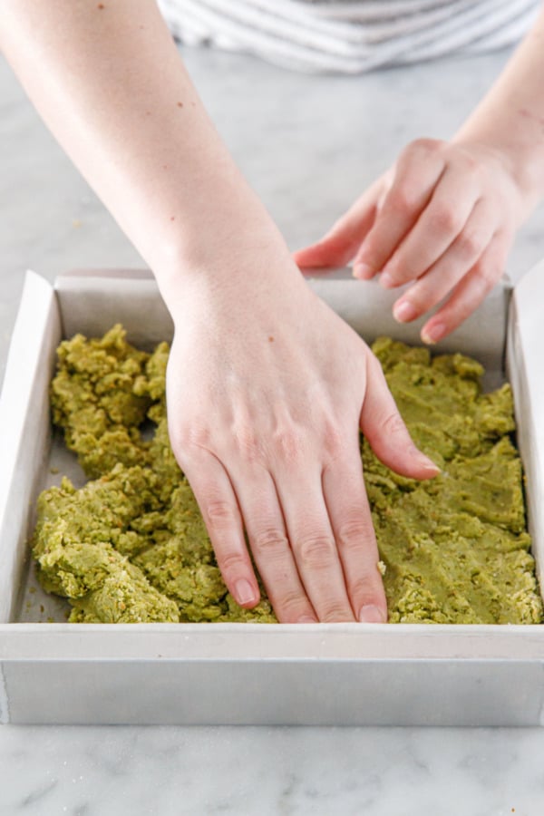 Pressing the shortbread dough into an even layer in a square baking pan