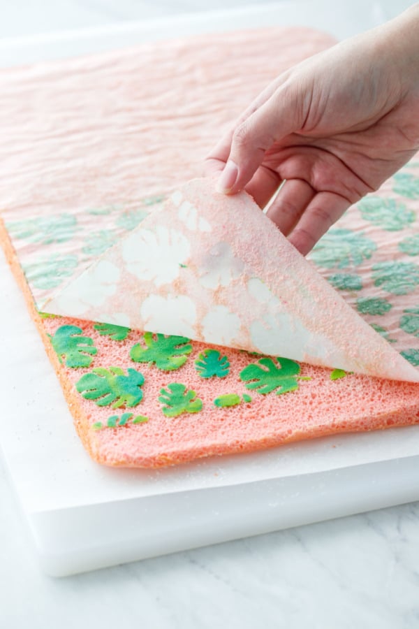 Peeling off the parchment paper to reveal the tropical leaf design