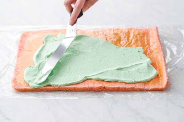 Spreading a layer of green pandan whipped cream on the cake