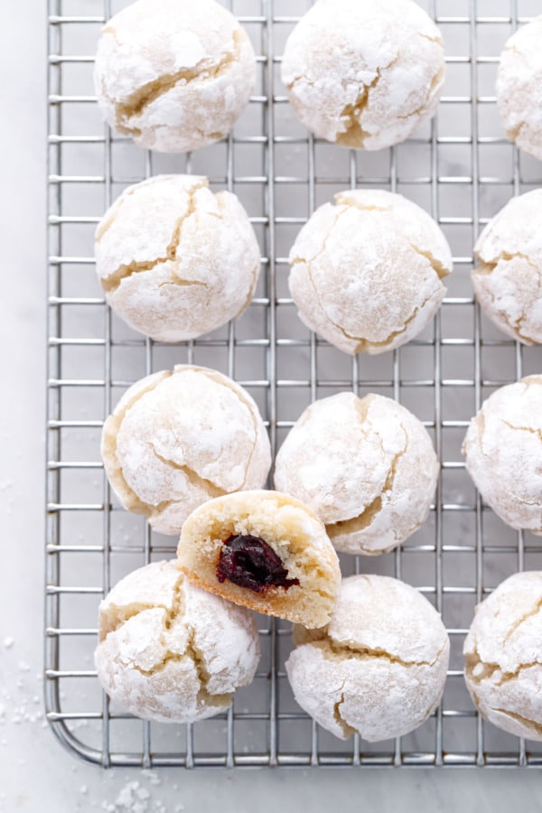 Overhead, Wire rack with rows of amaretti cookies, one cookie cut in half to show the amarena cherry hidden inside.