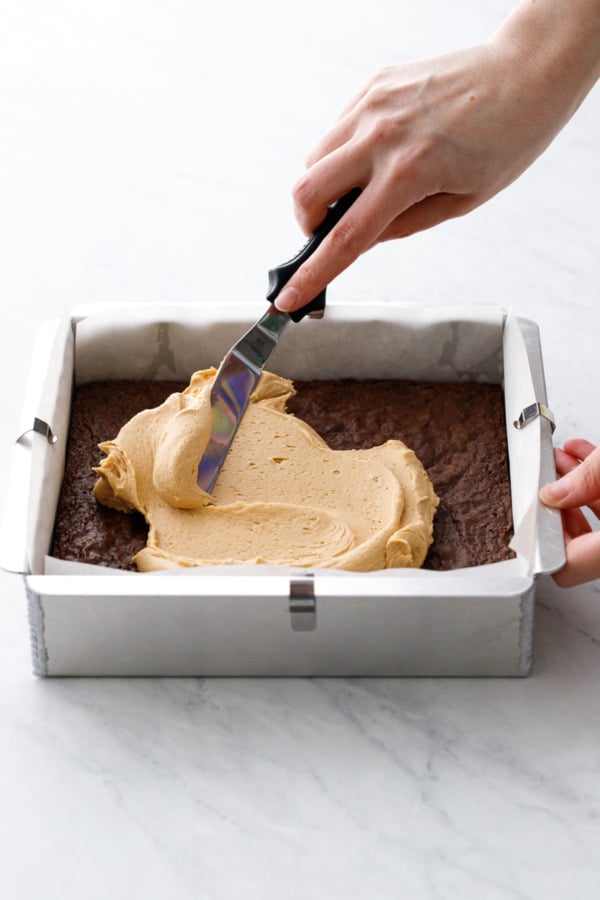 Spreading the peanut butter layer on top of the baked and cooled brownies