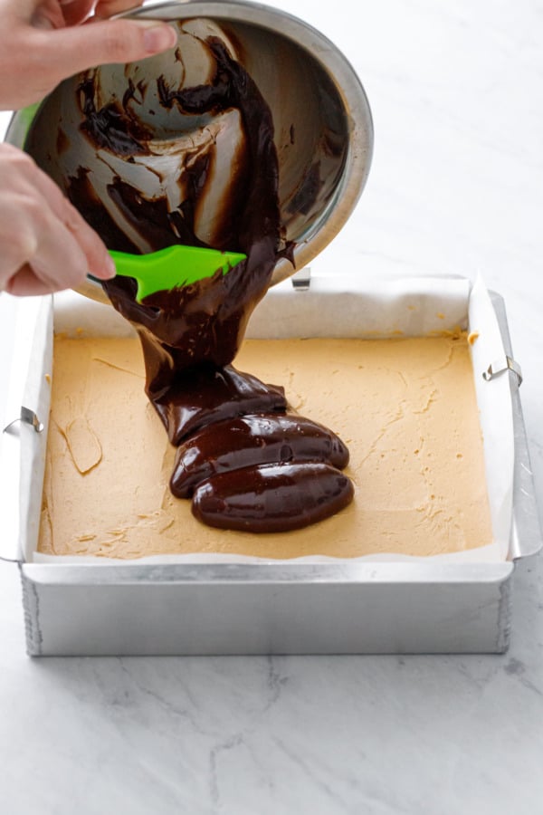 Pouring the milk chocolate ganache on top of the peanut butter layer.