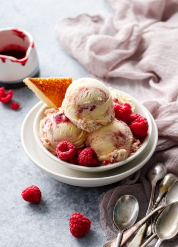 Bowl with stacked scoops of Toast & Jam Ice Cream, with a toast point and frozen raspberries as garnish