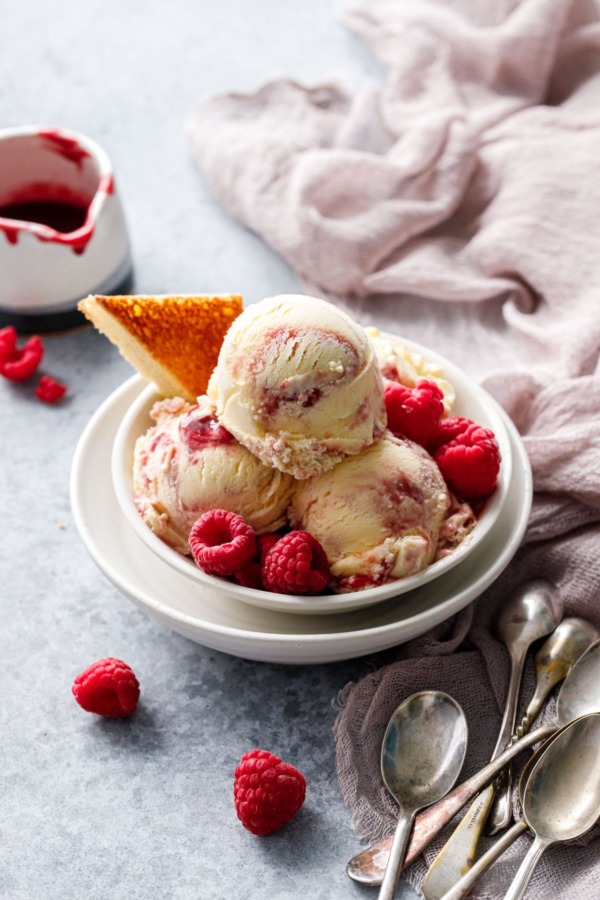 Bowl with stacked scoops of Toast & Jam Ice Cream, with a toast point and frozen raspberries as garnish