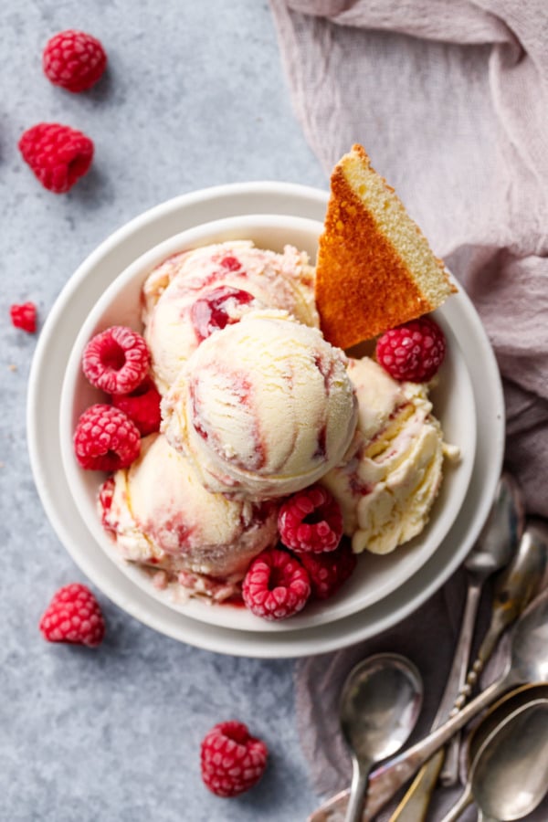 Overhead, bowls with stacked scoops of Toast & Jam Ice Cream, garnished with a toast point and frozen raspberries