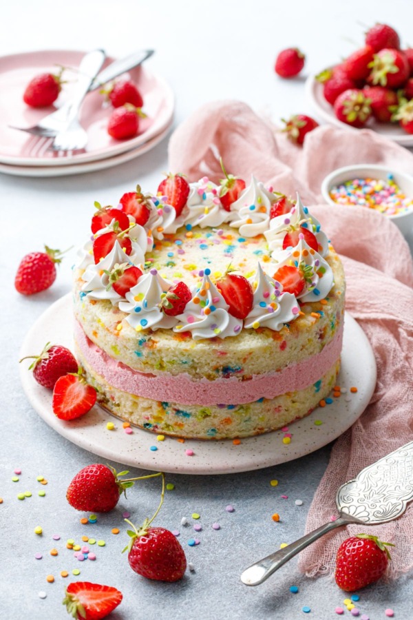 Strawberry Funfetti Ice Cream Cake on gray with pink linen and fresh berries