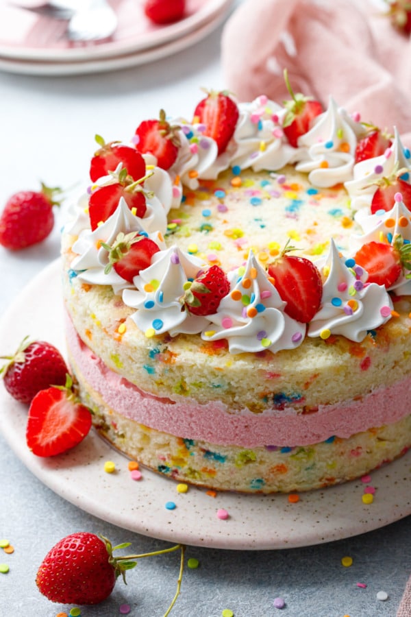 Closer detail shot of Strawberry Funfetti Ice Cream Cake with whipped cream and fresh berries