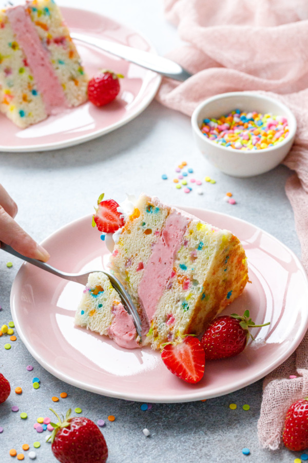 Fork cutting a piece out of a slice of Strawberry Funfetti Ice Cream Cake