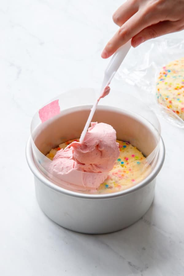 Assembling the Ice Cream Cake, spooning the ice cream on top of the first cake layer