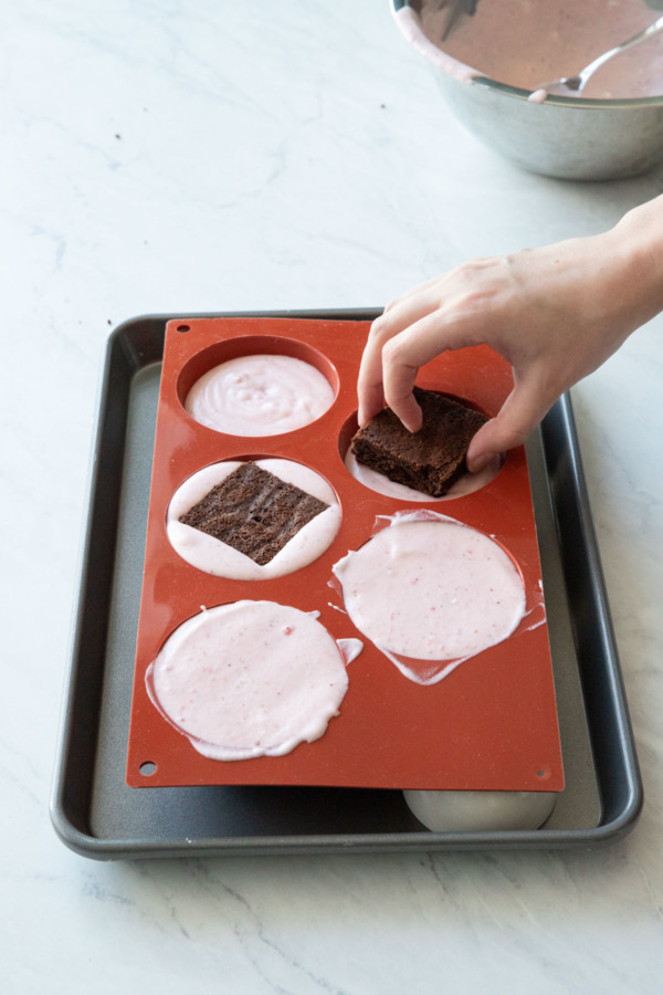 Placing the square of brownie in the mousse-filled silicone molds