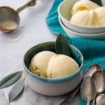 Two bowls of bay leaf ice cream on a gray background, with vintage spoons and ice cream scoop