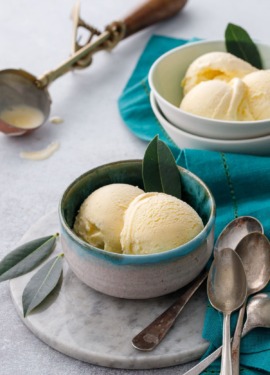 Two bowls of bay leaf ice cream on a gray background, with vintage spoons and ice cream scoop