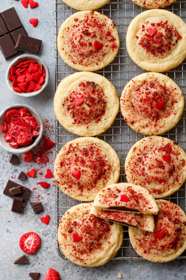 Overhead Chocolate Stuffed Strawberry Sugar Cookies on a wire rack, raw chocolate and freeze dried strawberries scattered on the side