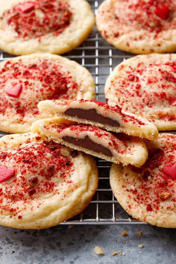 Closeup Chocolate Stuffed Strawberry Sugar Cookies on a wire rack, one cookie cut in half to show the chocolate filling