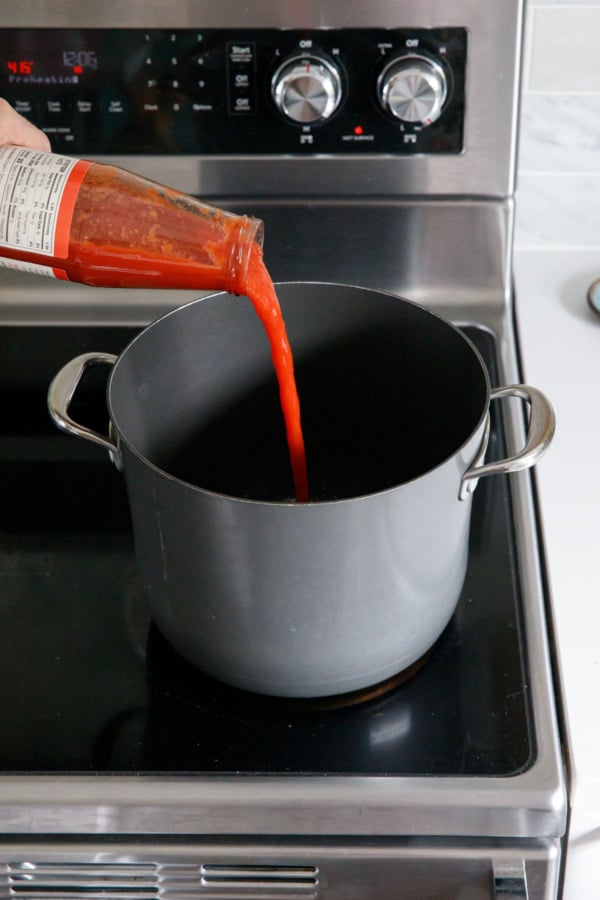 Pouring tomato puree into a stock pot