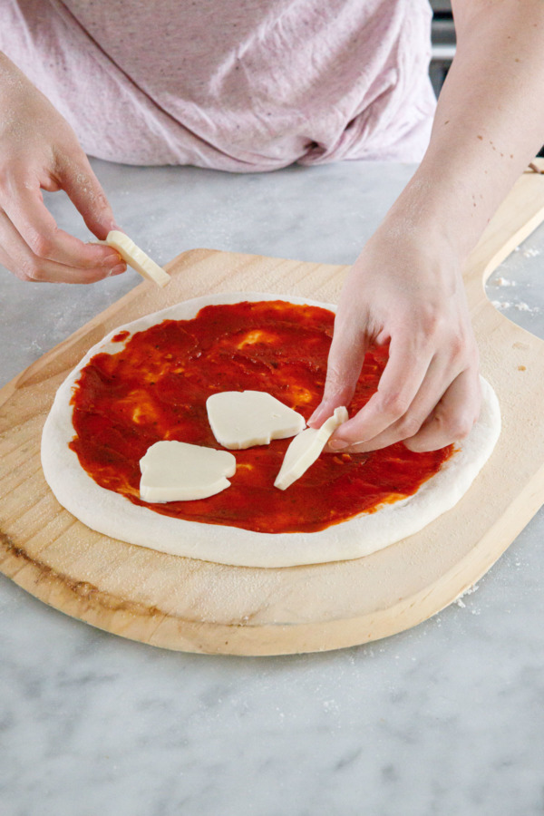 Placing rounds of mozzarella cheese onto a pizza