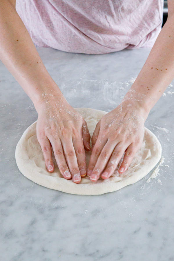 Lightly press and stretch dough further to form a subtle rim (take care not to deflate the dough as you do)