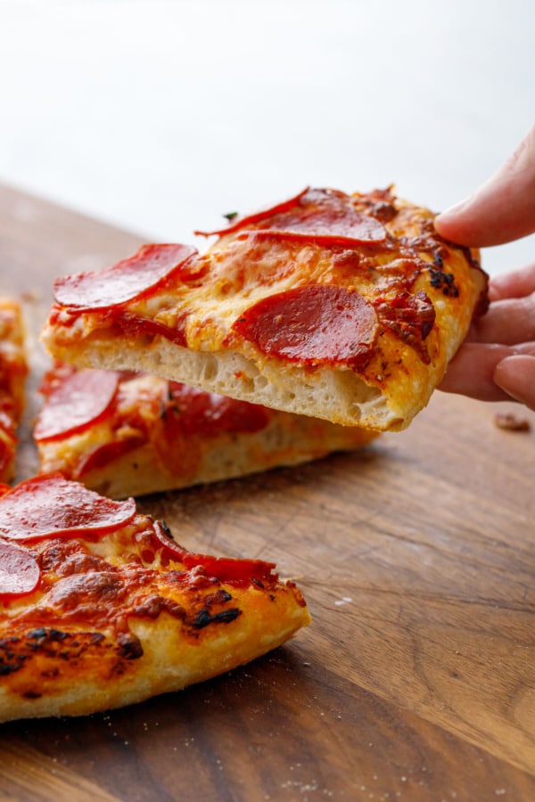 Closeup of sliced piece of pepperoni pizza to show texture of curst