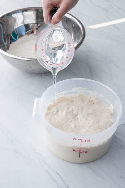 Pour water into the mature poolish, around the edges of the container to help it release.