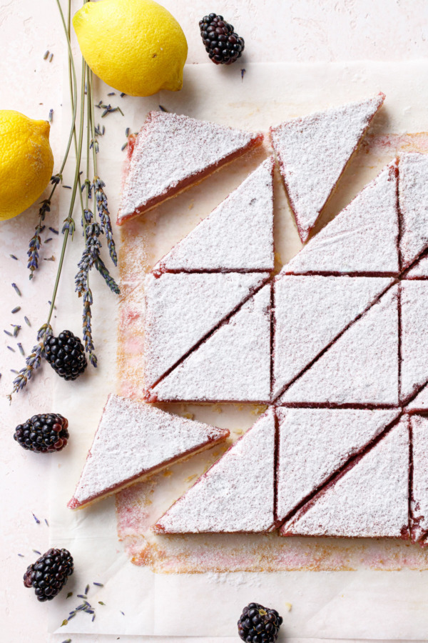 Overhead, Blackberry Lavender Lemon Bars cut into even triangles on parchment paper