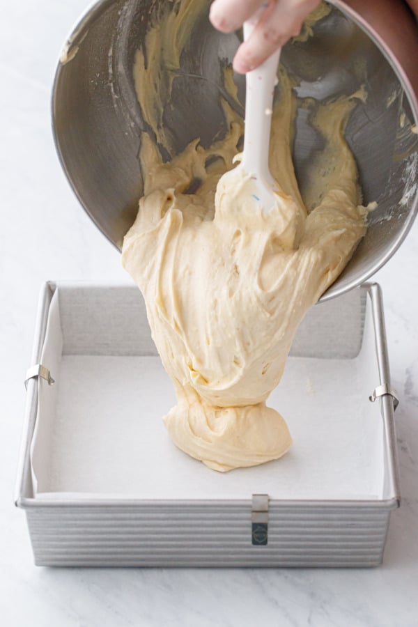 Pouring coffee cake batter into a parchment-lined baking pan