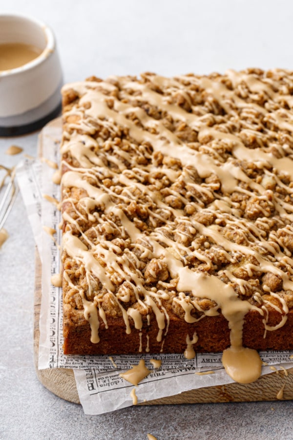 Square Espresso Crumb Coffee Cake on a wood board with glaze drizzled overtop and dripping down the sides