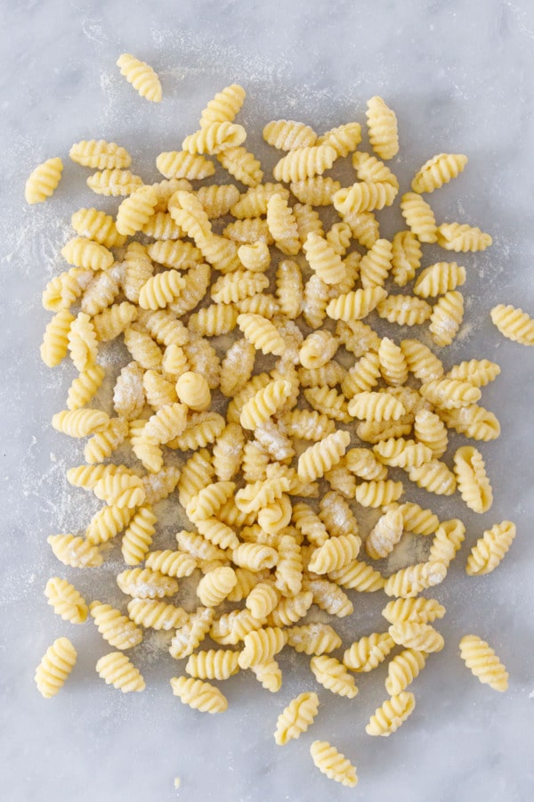 Overhead view pile of homemade gnochetti sardi pasta on a marble surface