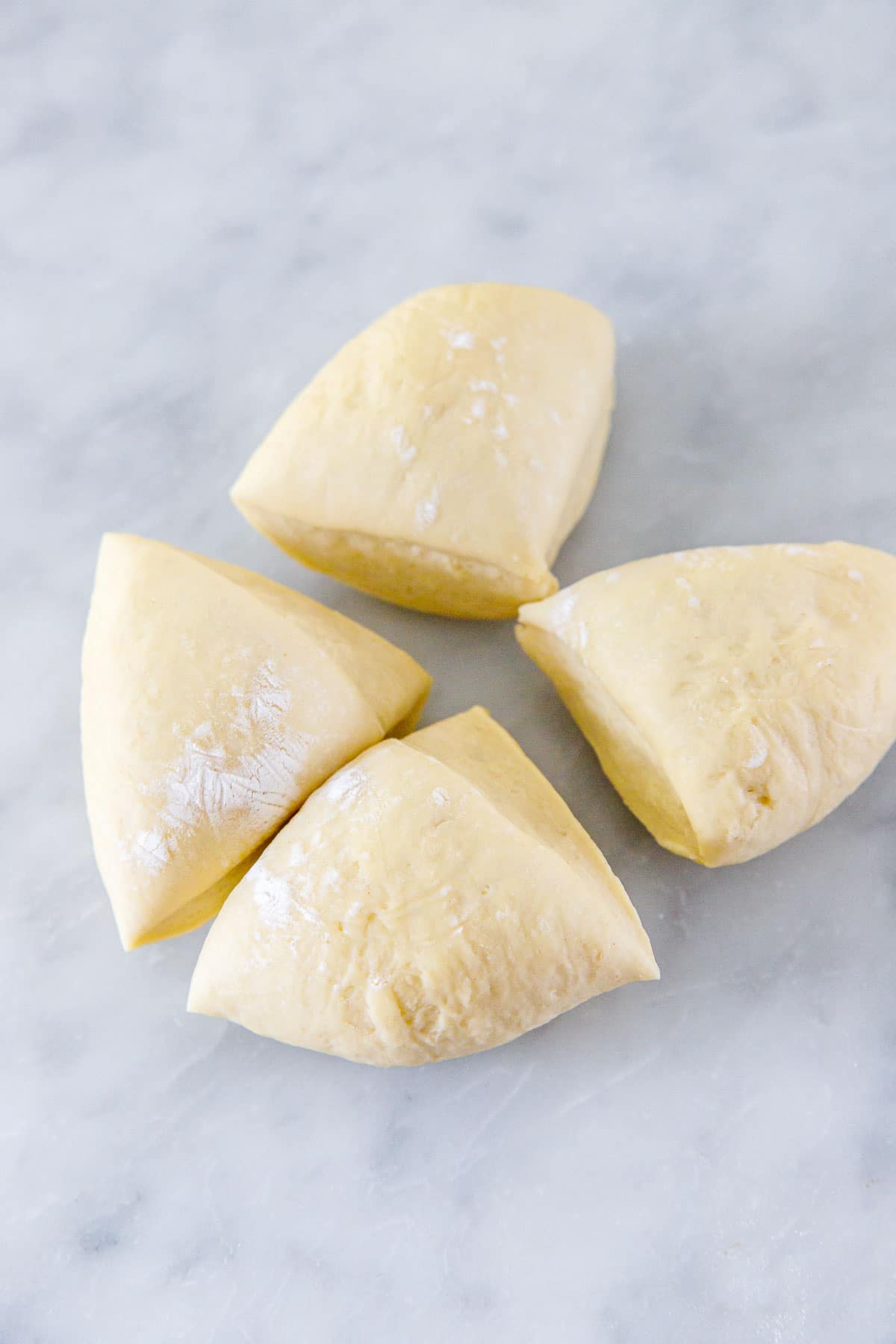 Ball of pasta dough cut into quarters.