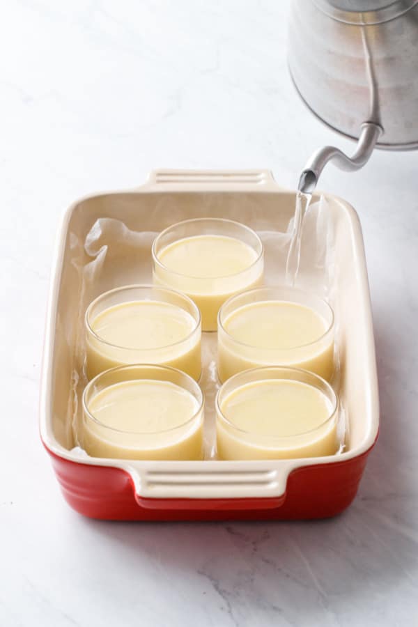 Filling up the baking dish around the ramekins with hot steaming water