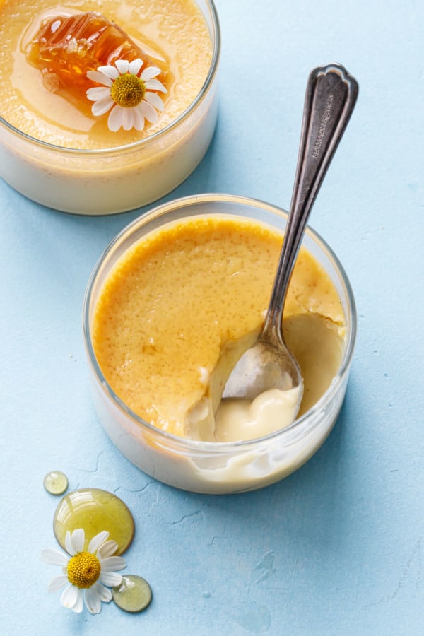 Spoonful of Honey Vanilla Pots de Crème in a glass ramekin, bit of custard on the spoon showing the silky texture